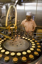 Man operating machine making cookies in window of shop.sugarsweetbakersbakerybiscuitsdietmachineryindustrialformationcirclecircularsmall businessFar EastAsia Asian Japanese Male Men Guy...