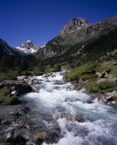 Vallee de Lutour looking south with snow covered peak of Pic de Labas 2927 m / 9586 ft and Tuc de Mounges cliff south of Cauterets. Fast flowing river in foreground.