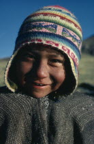 Head and shoulders portrait of a Bolivian boy smiling wearing a colourful wool chullo hat.American Colorful Happy Hispanic Kids Latin America Latino One individual Solo Lone Solitary South America