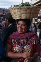 Kaqchiquel Indian woman named Modesta smiling wearing traditional dress and carrying a basket of green beans on her head at Patzun marketIndigenous people American Central America Classic Classical F...