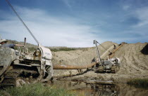 Constructing Trans Canada gas pipeline over Saskatchewan Prairies. Workers with construction vehicles laying pipe over swampAmerican Canadian North America