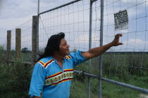 Independent Seminole Native American leader reading a No Trespassing notice posted on fence on agricultural land which is actually Indian land.North America United States of America American One indi...