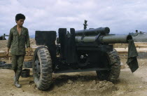 Vietnam War. Siege of Kontum. Montagnard soldier next to a howitzer artillery cannonKon TumAsian Southeast Asia Viet Nam Vietnamese One individual Solo Lone Solitary