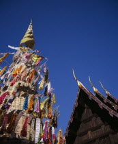 Wat Phran Tao.  Detail of pointed roof top of rare teak temple beside woven tower decorated by children with coloured paper flags and offerings. temple-monastery Asian Colored Kids Prathet Thai Raja...