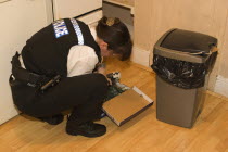 Policewoman searching kitchen of residential home during drugs bust.European One individual Solo Lone Solitary European One individual Solo Lone Solitary