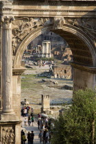 Tourists walking in the Forum with the Temple of The Vestals seen through the Arch of Septimius SeverusEuropean Italia Italian Roma Southern Europe History Holidaymakers Religion Tourism