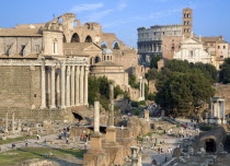 View of The Forum with the Colosseum rising behind the bell tower of the church of Santa Francesca Romana with tourists and the Temple of The Vestals on the right and the Temple of Antonius and Fausti...