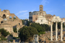 View of The Forum with the Colosseum rising behind the bell tower of the church of Santa Francesca Romana with tourists and the Temple of The Vestals and the three Corinthian columns of the Temple of...