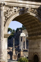 The floor of the Forum and the remains of the Temple of Castor and Pollux with three Corinthian Columns seen through the triumphal Arch of Septimius SeverusEuropean Italia Italian Roma Southern Europ...