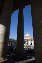 Vatican City The Basilica of St Peter and the square or Piazza San Pietro with tourists seen through the columns of BerniniEuropean Italia Italian Roma Southern Europe Catholic Principality Citta del...