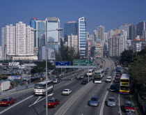 Multi-lane city road busy with traffic beside Causeway Bay boats and typhoon shelter with high rise city buildings beyond.Asia Asian Chinese Chungkuo Jhonggu Zhonggu