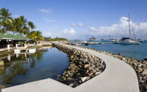 The concrete path around the shark pool at the Anchorage Yacht Club with boats moored in Clifton Harbour beyondCaribbean West Indies Windward Islands Holidaymakers Tourism Tourist