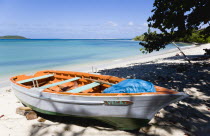 The calm clear blue water breaking on Paradise Beach in LEsterre Bay with Mabouya Island and Sandy Island in the distance. A small fishing boat sits on the beach out of the waterCaribbean Grenadian G...