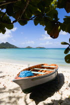 The calm clear blue water breaking on Paradise Beach in LEsterre Bay with Cistern Point and the Sister Rocks in the distance. A small fishing boat sits on the sandy shoreline out of the waterCaribbea...