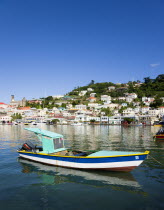 Fishing boat moored in the Carenage harbour of the capital city of St Georges with houses and the roofless cathedral damaged in Hurricane Ivan on the nearby hillCaribbean Grenadian Greneda West Indie...