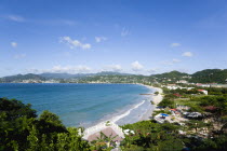 Waves of the aquamarine sea breaking on the two mile stretch of Grand Anse Beach with people on the white sandy beach and the capital city of St Georges in the distanceCaribbean Grenadian Greneda Wes...