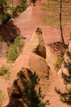 Red ochre cliffs and outcrops and pine trees in the area known as the Needle Cirque.Ochre Trail European French Western Europe