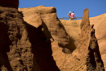 Colorado Provencal.  Cheminee de Fee or Fairy Chimneys.  Two tourists admire the view from top of eroded ochre rock.Ochre Trail European French Western Europe 2 Holidaymakers Tourism