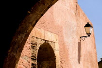 Roussillon.  Architectural detail of archway framing street light on red exterior wall of town building. lantern European French Western Europe 1 Single unitary One individual Solo Lone Solitary