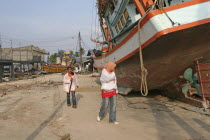 Tsunami. People walk past boats that have been pushed onto the streets in the village  nothing is left standing in. 2500 people are pressumed dead. 125kms north of Phuket on the 2nd Jan.Asian Ecology...