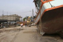 Tsunami. People walk past boats that have been pushed onto the streets in the village  nothing is left standing in the village 2500 people are pressumed dead 125kms north of Phuket on the 2nd JanAsia...