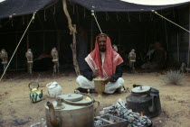 Bedouin man sitting outside his tent with row of pirched falcons behind him Male Men Guy