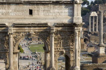 The Forum with the triumphal Arch of Septimus Severus in the foreground and the three Corinthian columns of the Temple of Castor and Pollux in the distance with tourists walking aroundEuropean Italia...