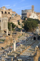 View of the Forum with the Colosseum rising behind the bell tower of the church of Santa Francesca Romana with tourists walking past the ruins on the floor of the ForumEuropean Italia Italian Roma So...