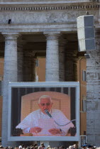 Vatican City Pilgrims in St Peters Square for the wednesday Papal Audience in front of the Basilica watching Pope Benedict XVI Joseph Alois Radzinger with a cardinal on a large video TV monitor displa...