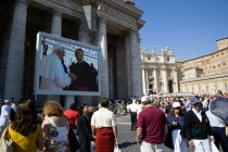 Vatican City Pilgrims in St Peters Square for the wednesday Papal Audience in front of the Basilica watching Pope Benedict XVI Joseph Alois Radzinger with a cardinal on a large video TV monitor displa...