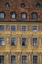 Detail of building facade with tromp l oeil painted mural creating effect of statuary and carved stonework.  Red tiled roof and multiple windows. optical illusion reality Eastern Europe European Poli...