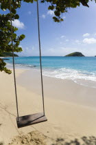 Empty swing hanging from a tree over the beach and breaking waves on Glossy Bay BeachBeaches Resort Sand Sandy Scenic Seaside Shore Tourism West Indies Caribbean Windward Islands Beaches Resort Sand...