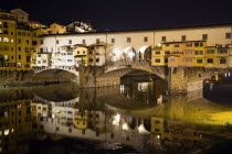The 14th century Ponte Vecchio or Old Bridge across the River Arno illuminated at night with sightseers on the bridgeEuropean Italia Italian Southern Europe Toscana Tuscan Firenze History Holidaymakers Nite Tourism Tourist