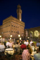 People eating in The Piazza della Signoria at night with the Palazzo Vecchio and campanile bell tower illuminated beside the Loggia dei LanziEuropean Italia Italian Southern Europe Toscana Tuscan Fir...