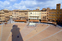 Shadow of the Torre del Mangia campanile belltower in the Piazza del Campo with surrounding buildings busy with touristsEuropean Italia Italian Southern Europe Toscana Tuscan History Holidaymakers To...