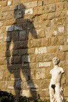 The copy of the statue of David by Michelangelo casting its shadow on the wall of the Palazzo Vecchio in the Piazza della Signoria beside an armless statueEuropean Italia Italian Southern Europe Tosc...