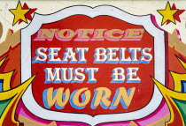 Findon village Sheep Fair Colourful red sign on a fairground ride that reads Notice Seat Belts Must Be Worn.Great Britain Northern Europe UK United Kingdom British Isles European