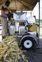 Man feeding sugar cane into a mobile cane juice machine beside Grand Anse beach.Caribbean Destination Destinations Grenadian Greneda West Indies Grenada Cell Cellular Farming Agraian Agricultural Gro...