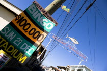 Town of Gouyave with a metal sign above the main road through the fishing town reading Welcome To Gouyave The Fishing Capital Of Grenada with a sign on a lamp post advertising the weekly bingo .Carib...