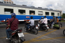 People on scooters at level crossing waiting train to pass.TransportationLifestyleDrivingTrain crossingMoppetMotorbikeMotorcycleBikeTrafficSummerHolidaysVacationUrbanCityCity life Asian...