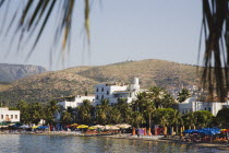 View across beach and inland on clear  early season summer day.  With line of coloured parasols and sunbeds for hire.Turkish Aegean coastmediterraneanresortformerly HalicarnassusHalikarnasregion...