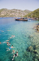 Gulet pleasure boat moored off Gemiler or St Nicholas Island with tourists swimming in perfect clear water in early summer season over Byzantine ruins under water.Fethiyeformerly Telmessosformerly...