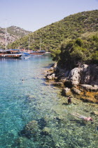 Gulet pleasure boat moored off Gemiler or St Nicholas Island with tourists swimming in perfect clear water in early summer season over Byzantine ruins under water.Fethiyeformerly Telmessosformerly...