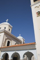 Agia Paraskevi Greek Orthodox Church.  Angled part view of white and cream facade with arched colonnade with red tiled roof.  Greek IslandsAegeanMediterraneanKossummerseasonholidaydestination...