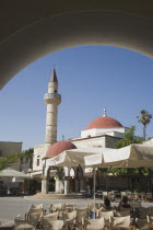 Defterdar Mosque on the town square  Plateia Eleftherias framed by arch in foreground.  The island was formerly an Ottoman territory. Greek IslandsAegeanMediterraneanKossummerseasonholidaydest...