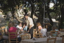 People eating at outside cafe tables with backdrop of trees.Resort Summerearly season AegeanHolidayDestination Destinations Ellada European Greek Southern Europe Bar Bistro Restaurant