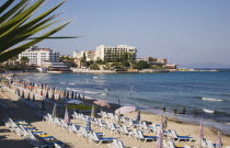 Beach with line of sun loungers and umbrellas  apartments and hotels beyond.TurkishAegeancoastresortsummersunshineearly summer seasonMediterraneanholidayDestination Destinations Ellada Europ...