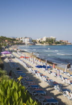 Beach with line of sun loungers and umbrellas  apartments and hotels beyond.TurkishAegeancoastresortsummersunshineearly summer seasonMediterraneanholidayDestination Destinations Ellada Europ...