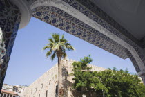 Crenellated building and palm tree framed by arch decorated with painted mosaic titles.TurkishAegeancoastresortsummersunshineearly summer seasonMediterraneanholidayDestination Destinations E...