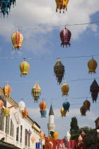 Coloured lanterns hanging between partly seen buildings against blue sky with white clouds.TurkishAegeancoastresortSummersunshineearly Summer seasonholidaydestinationdestinations ElladaEuro...